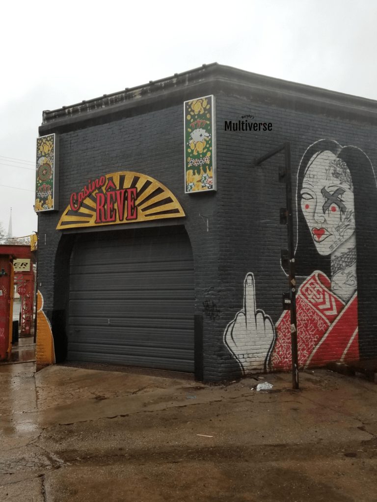 a set photo of a building labelled Casino Reve, on the side a mural of a woman with her middle finger raised
