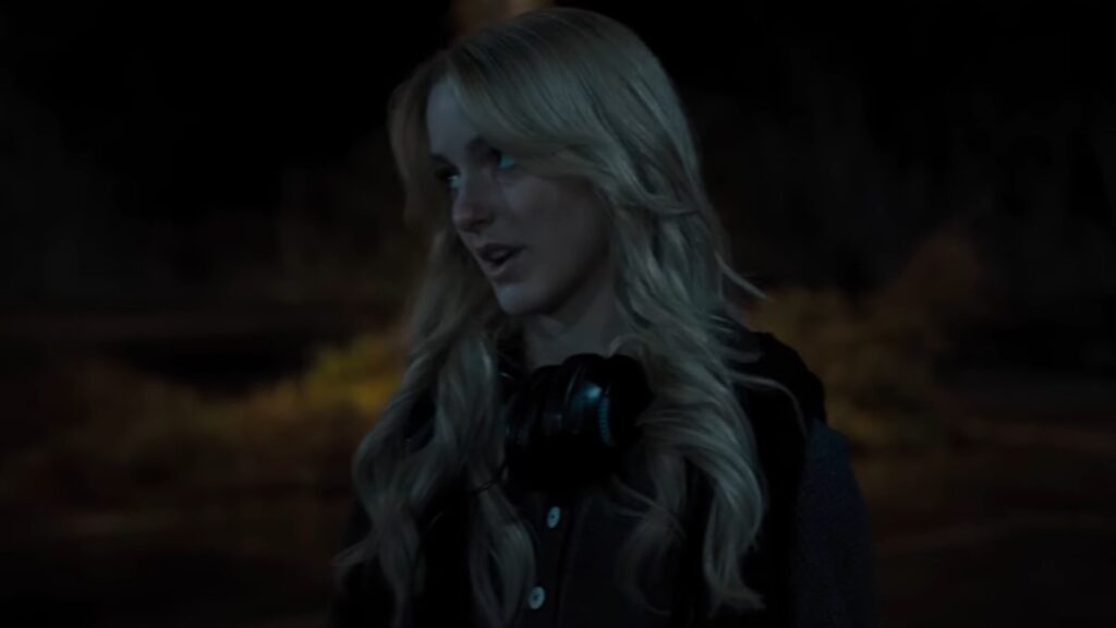 Elizabeth Lail as Vanessa standing outside at night wearing headphones in Five Nights at Freddy’s 2