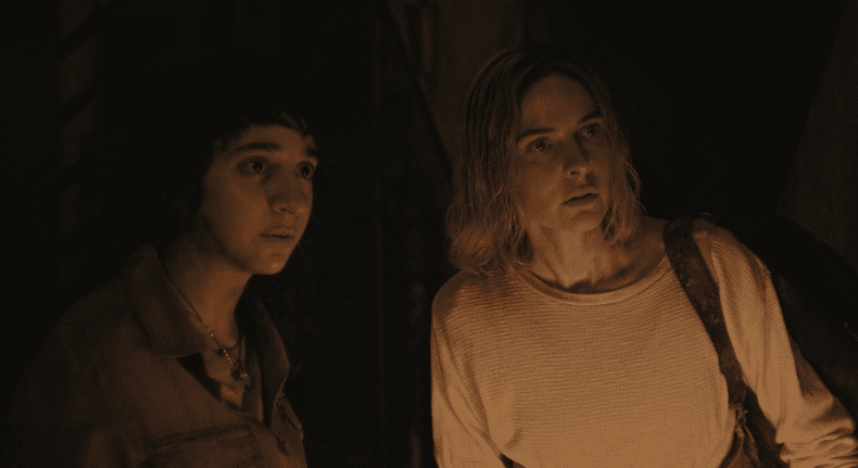 Rashida Jones and Rebecca Ferguson look ahead, lit by warm light from Silo season 2