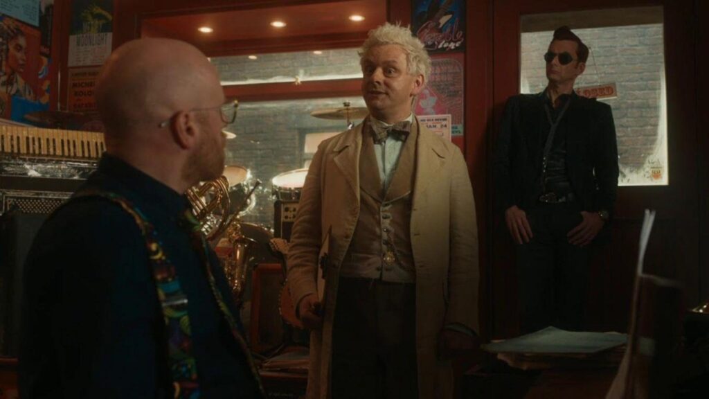 Michael Sheen and David Tennant stand with Jon Hamm in shop scene, from Good Omens season 2