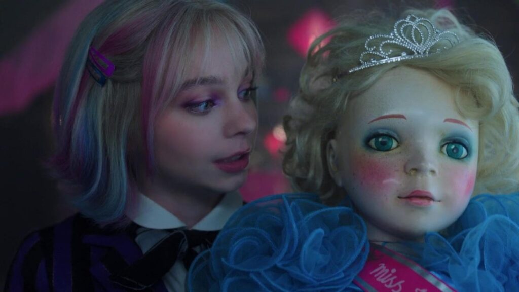 Emma Myers as Enid Sinclair holding doll colorful dorm scene in Wednesday season 3