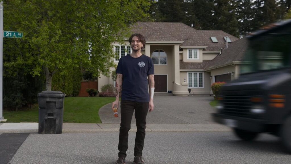 Young man stands smiling outside suburban home in Final Destination: Bloodlines