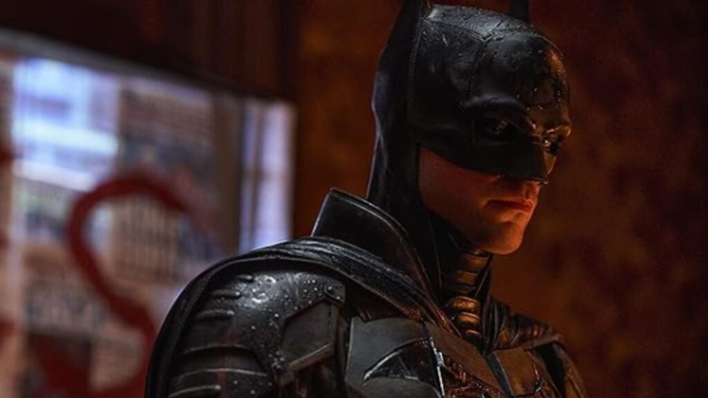 Robert Pattinson as Bruce Wayne in The Batman standing beside Gotham crime evidence