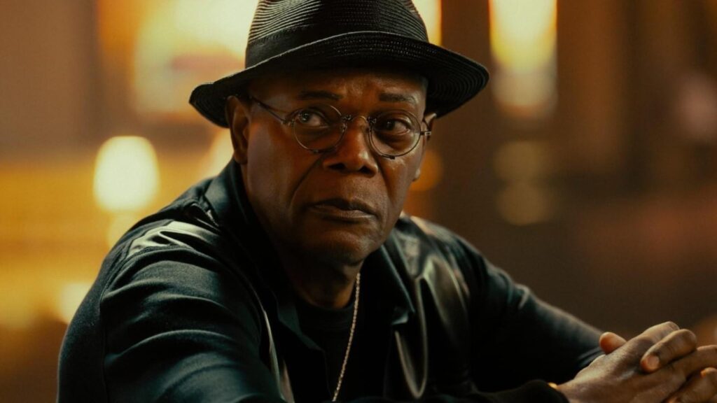 Samuel L Jackson sits under warm lighting in a serious moment Tulsa King season 3