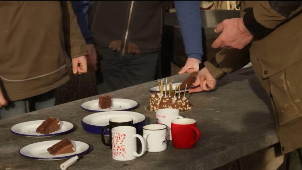 Jeremy Clarkson and farm crew celebrate birthday gathering with chocolate cake outdoors, from Clarkson's Farm season 5
