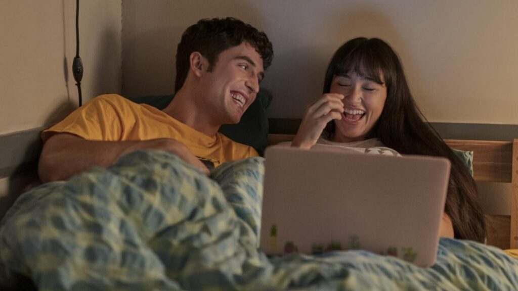 Adam DiMarco and Mary Beth Barone laughing in bed, from Overcompensating Season 2