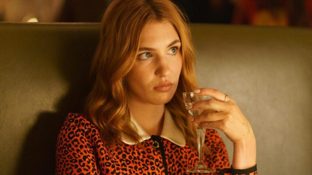 Sophie Nélisse as Rose Landry holding a drink with concerned expression in Heated Rivalry