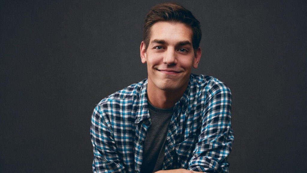 Portrait of Matt Rogers smiling at the camera while wearing a blue plaid shirt.