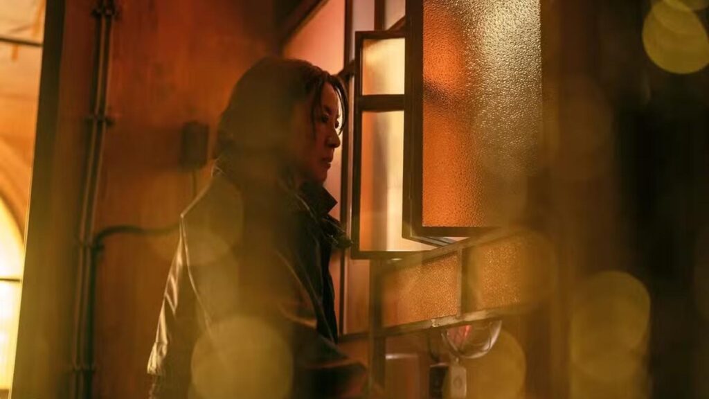 Michelle Yeoh as Olwen stands beside illuminated window in atmospheric futuristic setting from Blade Runner 2099