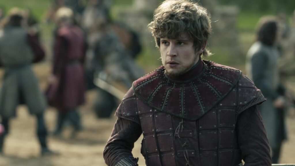 Shaun Thomas as Ser Raymun 'The Reluctant' Fossoway in youthful armor standing alert during village gathering in A Knight of the Seven Kingdoms